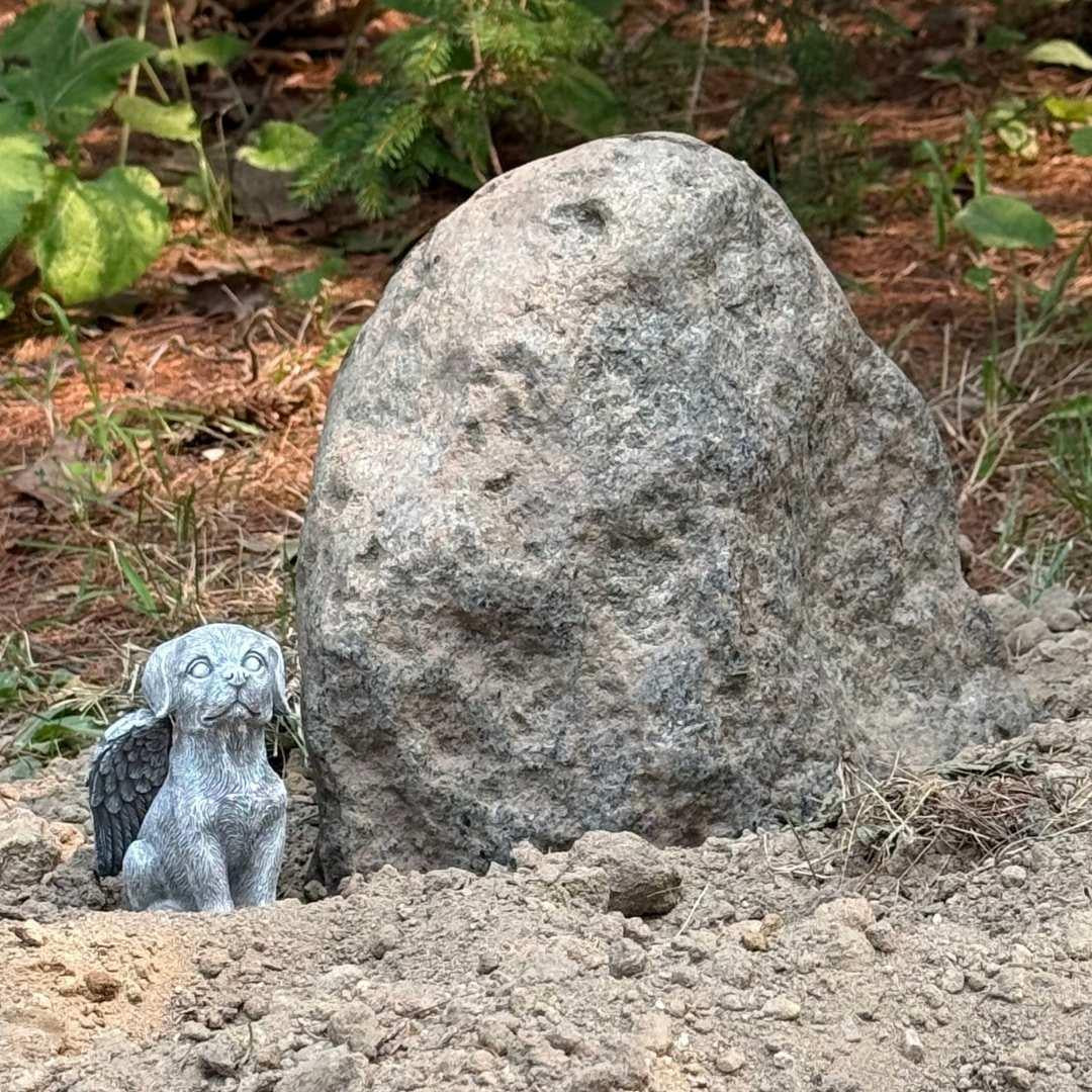 A stone grave marker with a small stone angel dog statue beside it
